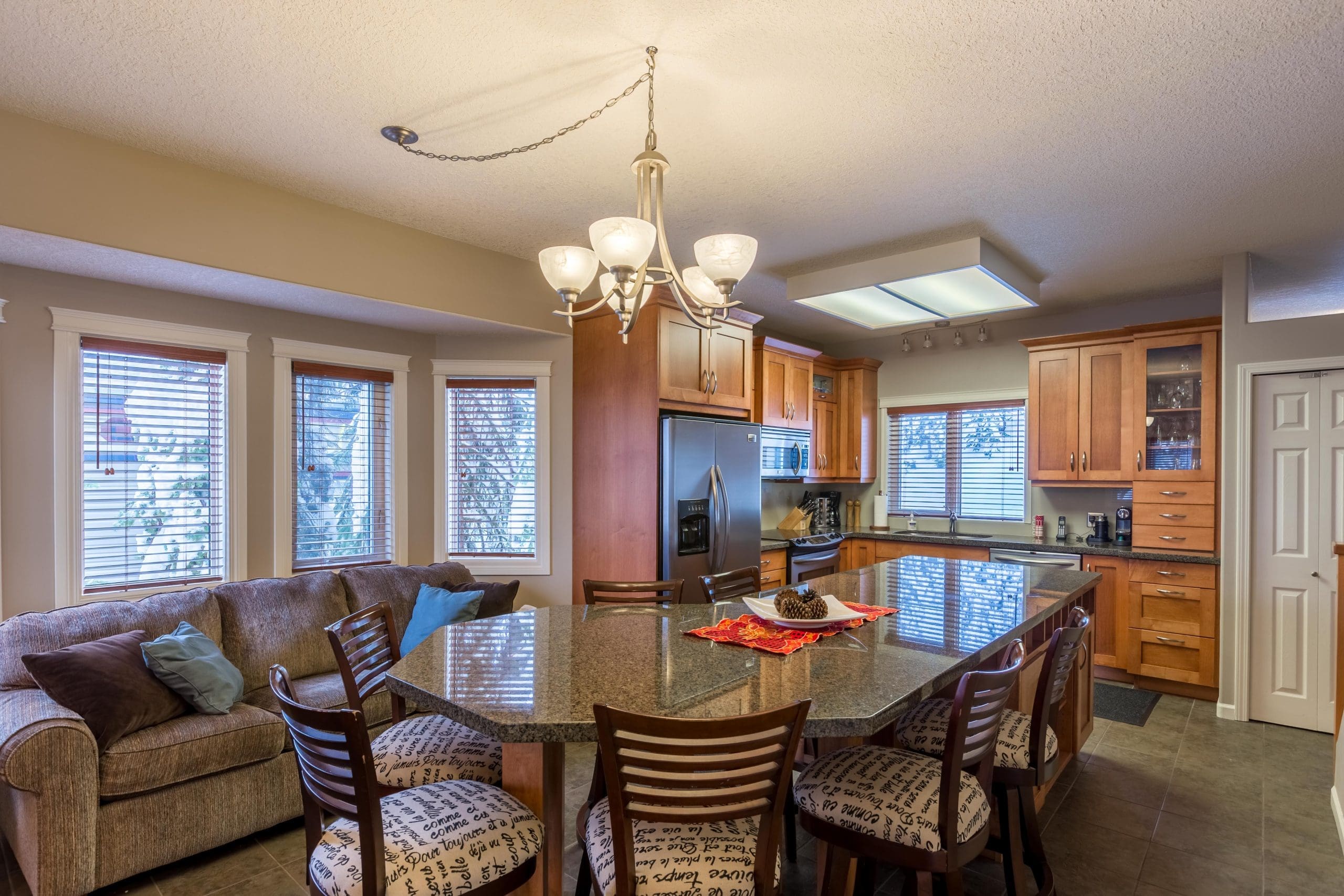 Kitchen Island/sitting area of beautiful home nestled in the trees. Bright open windows, open concept living. Ski right out from the backyard to the skiway. Private hot tub, laundry, gas fireplace, BBQ on deck. Pet-friendly too!